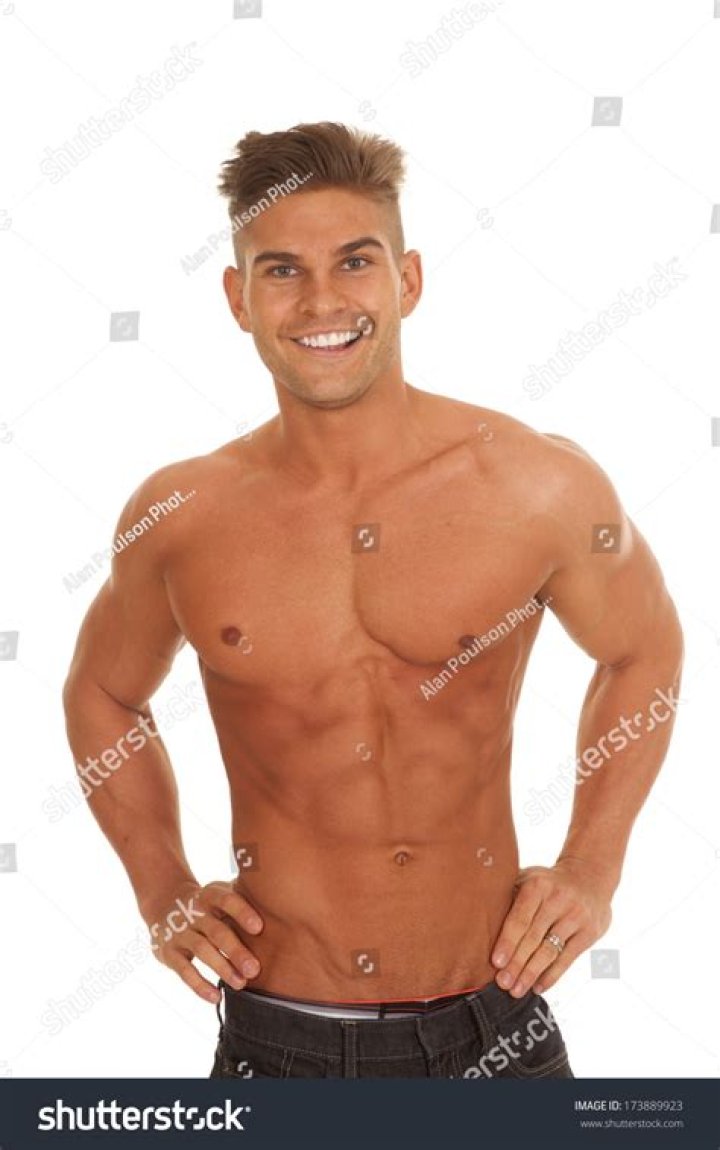 a man without a shirt standing in front of a pool with his hands on his