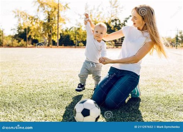Happy Mom with Son Playing with Soccer Ball on Field, Outdoors Stock